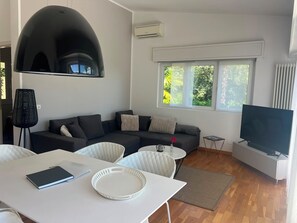 A modern living room with a sectional sofa, a flat-screen TV, and a dining area with a table and chairs. - La nostra casa - Welcome to Ghiffa on Lake Maggiore (Ghiffa)