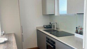 A compact kitchen with a built-in oven, a sink, and a window above the countertop.