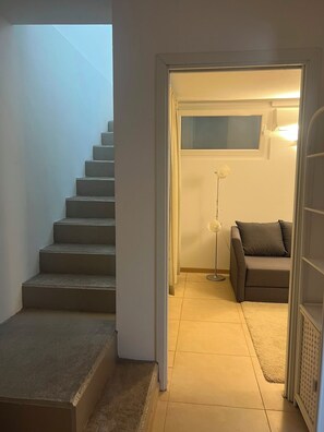 Een trap die uitkomt op een plateau met een bank en vloerlamp.