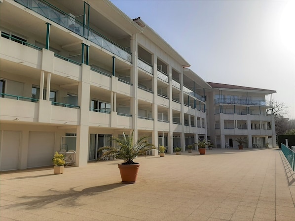 A multi-story building with balconies, potted plants, and a tiled courtyard.