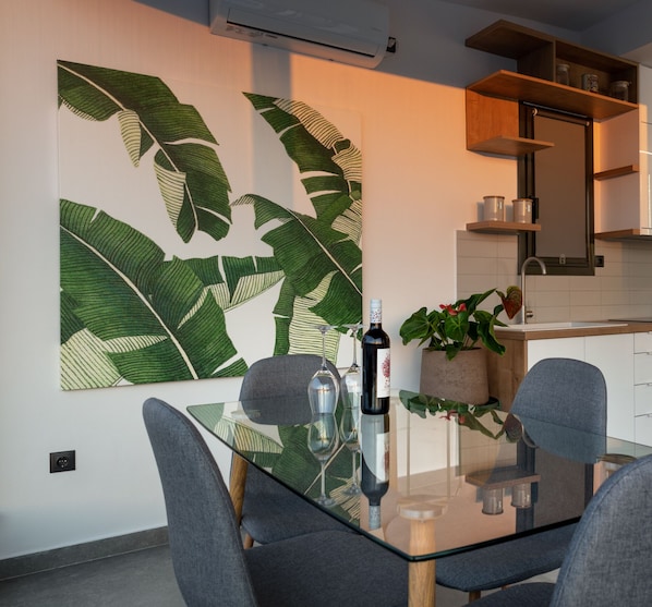 A modern kitchen with white cabinets, a wooden shelf with jars, and a large green leaf-patterned artwork on the wall. - 59m² homm Loft- Penthouse with Acropolis View,2ppl (Athens)