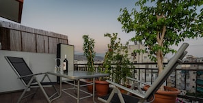 A balcony with a table, two chairs, a bottle, and potted plants. - 59m² homm Loft- Penthouse with Acropolis View,2ppl (Athens)