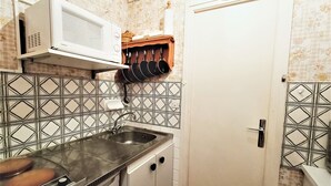 A compact kitchen with a microwave, stove, and hanging pots. - Bright and functional studio ideally located in Aix-les-Bains (Aix-les-Bains)