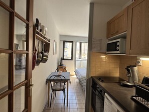 Eine kleine Küche mit Esstisch und Stühlen, einer Mikrowelle und einer Kaffeemaschine.