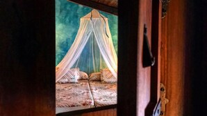 A wooden room with a bed under a canopy, a window, and a door. - Casa rural la Quinta de Malu Romantic hotel in Cuenca Romantic getaways (Valeria)