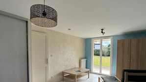 A spacious room with a bed, a table, a chair, and a view of the outdoors through a sliding door.