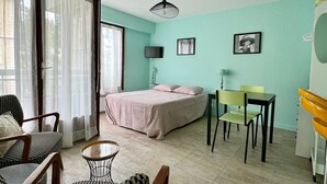A bedroom with a bed, a desk, and a chair. There is a window with curtains and a door. - Bright and functional studio in Aix-les-Bains, pets allowed (Aix-les-Bains)