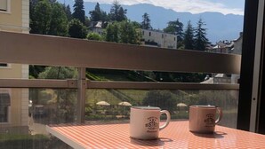 A balcony with a checkered tablecloth and two coffee mugs on a table, overlooking a scenic view of houses and mountains. - Bright and functional studio in Aix-les-Bains, pets allowed (Aix-les-Bains)