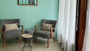 A room with teal walls, two patterned armchairs, a small round ottoman, and a wire coffee table. - Bright and functional studio in Aix-les-Bains, pets allowed (Aix-les-Bains)