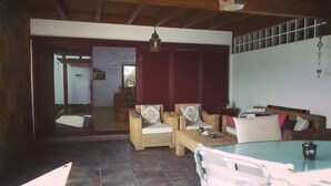 A spacious living area with a dining table, wicker sofas, and a large window. - PRIVATE GARDEN & HEATED POOL, WIFI Fiber 600Mb / s Total comfort and total privacy (La Oliva)