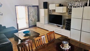 A modern living room with a TV, white cabinets, a dining table, and a blue bowl. - PRIVATE GARDEN & HEATED POOL, WIFI Fiber 600Mb / s Total comfort and total privacy (La Oliva)