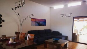 A living room with a dark-colored sofa, a dining table with chairs, a coffee table, and a painting on the wall. - PRIVATE GARDEN & HEATED POOL, WIFI Fiber 600Mb / s Total comfort and total privacy (La Oliva)