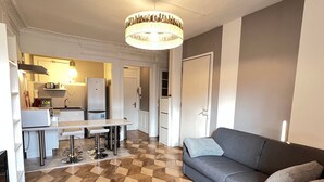 Een moderne woonkamer met een grijze bank, een witte salontafel en een vloer met een patroon.
