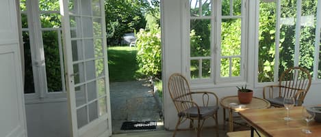 A room with a wooden table, two wicker chairs, and a potted plant.