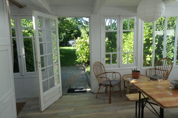 A room with a wooden table, two wicker chairs, and a potted plant.