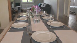 Ein Esstisch mit Tellern, Gläsern und einer Blumenvase.