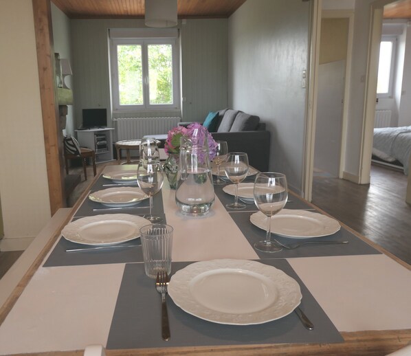 Une table à manger dressée avec des assiettes, des verres et un vase de fleurs.