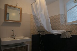 Une salle de bain avec un lavabo, un miroir, une douche et des carreaux décorés.