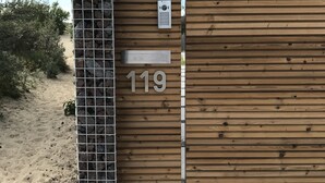 A wooden gate with the number 119, a metal gate, and a small device on the wall. - In De Duinen (Middelkerke)