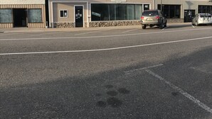 Ein Gebäude mit Schaufenster, Parkplatz und Straße.