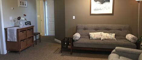 A living room with a grey sofa, a small table, wicker baskets, and a framed picture on the wall.