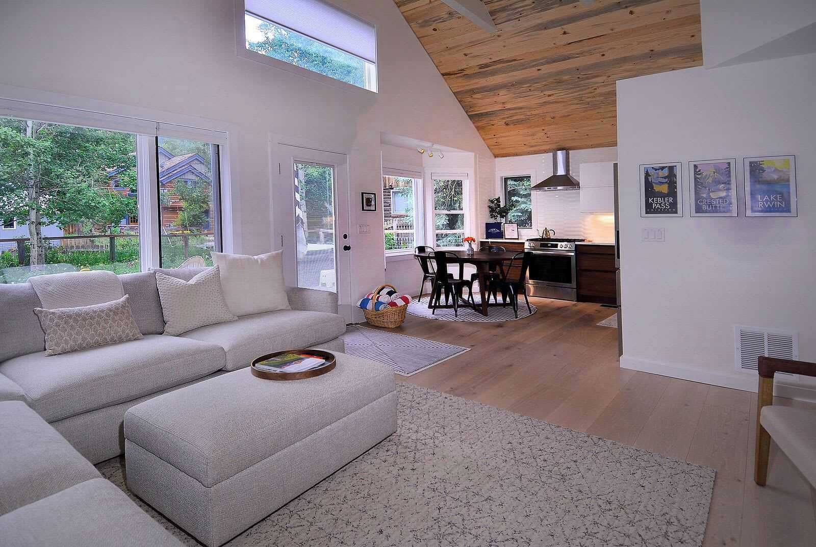 A modern living room with a sofa, dining table, and kitchen area.