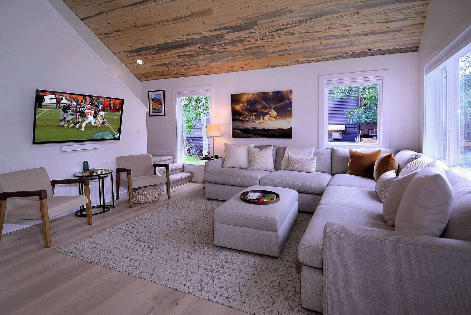 A modern living room with a sectional sofa, a flat-screen TV, and artwork on the walls.