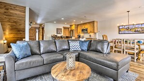 Een moderne woonkamer met een hoekbank, een ronde salontafel en een eethoek met houten stoelen en een tafel.