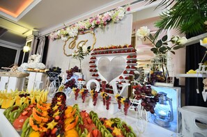 A fruit and cheese board with a decorative heart-shaped centerpiece and a floral arrangement above. - Hotel Nevada (Constanta)