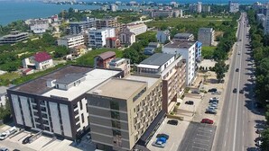 A multi-story hotel with a modern design, located adjacent to a busy road with visible parking. - Hotel Nevada (Constanta)