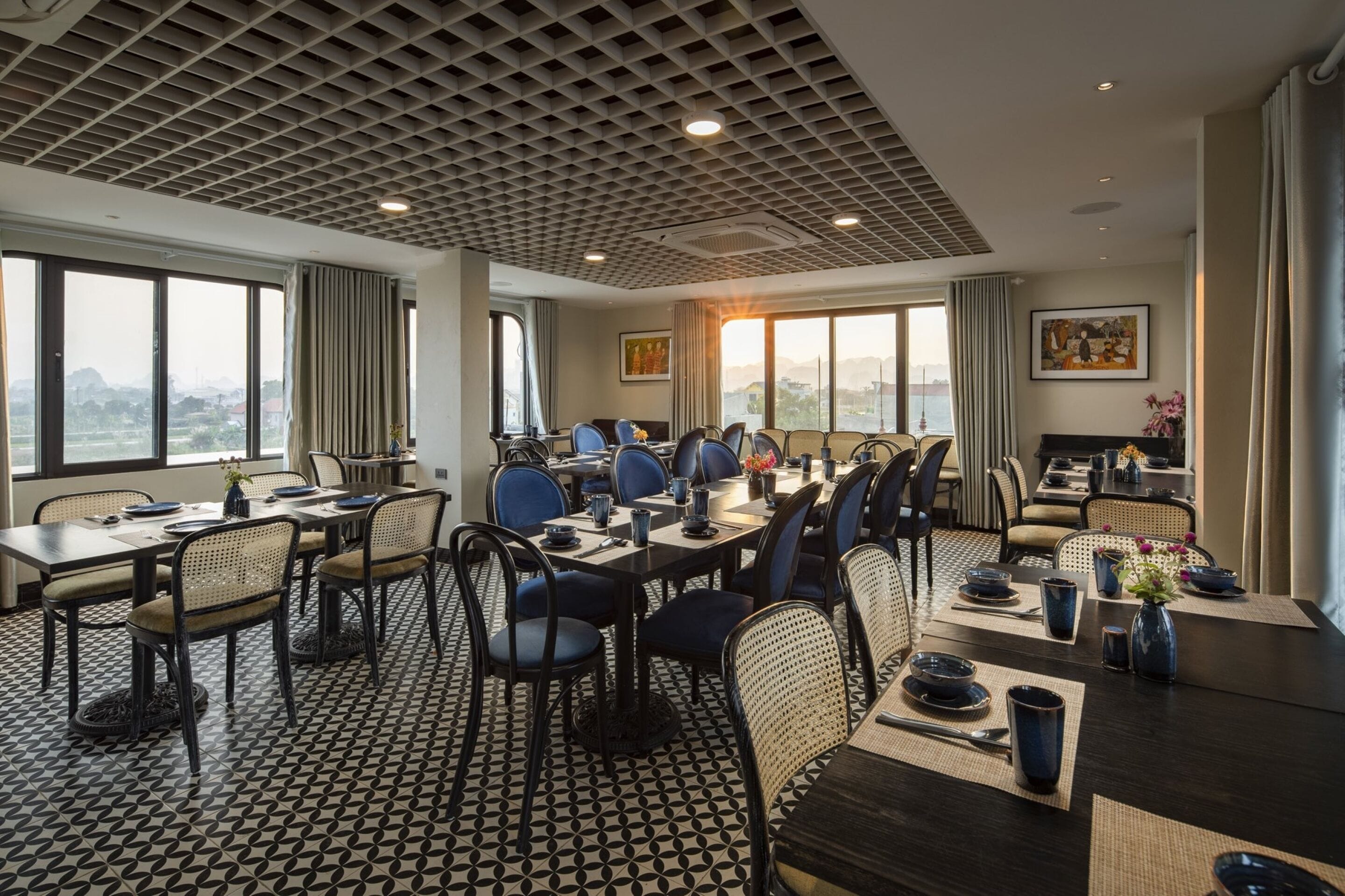 A dining area with a geometric patterned floor, a ceiling with a grid design, and large windows offering a view of the cityscape.