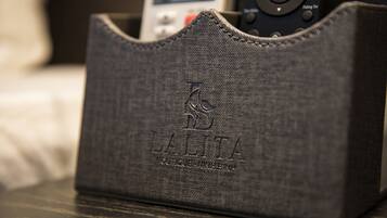 Une coque en tissu à texture sombre, ornée de motifs en relief et d’un logo, posée sur une surface en bois.