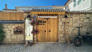 A traditional wooden gate with a stone wall, a stone staircase, and a bicycle parked to the right.