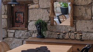A wooden table with chairs, a stone wall, a wooden fence, and a tiled roof.