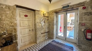 A stone-walled room with a checkered floor, a wooden cabinet, a sign indicating an exit, and a fire extinguisher.