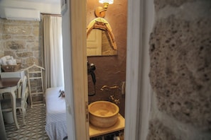 Bathroom features a stone wall, wooden vanity, and a large round sink.