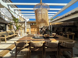 An outdoor dining area with wicker chairs, a wooden table, and a hanging light fixture.