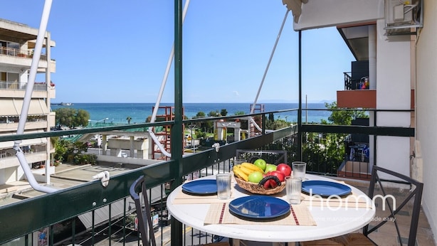 Ein Balkon mit Tisch für zwei Personen, mit Blick auf die Küste.