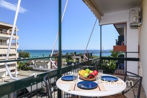 A balcony with a table set for two, overlooking a coastal view. - 90m² homm Sea View Apartment in Alimos (Alimos)
