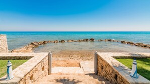 A stone pathway leading to a circular water feature with a clear view of the sea.