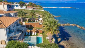 A coastal property with a swimming pool, sun loungers, and a view of the sea.