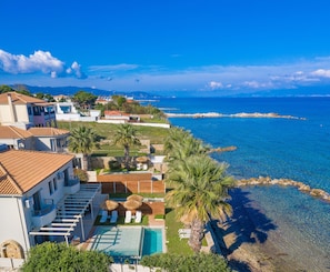 A coastal property with a swimming pool, sun loungers, and a view of the sea.