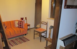 Un salón acogedor con un sofá, una silla de madera, una mesita y un radiador.