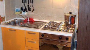 A kitchen with orange cabinets, a stainless steel stove, and a sink.