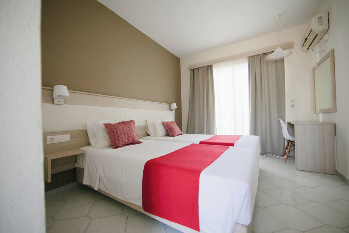 A hotel room with two beds, a desk, and a chair.