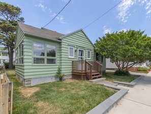 A single-story house with a front porch, a small deck, and a front yard.