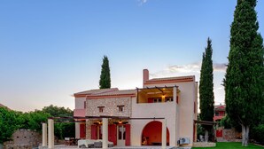 A two-story house with a stone facade, a red roof, and a covered patio area.