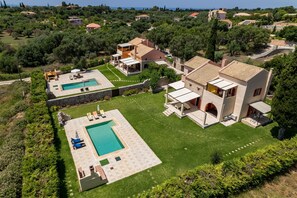 Uma vila com piscina, jardim e vista para o mar.