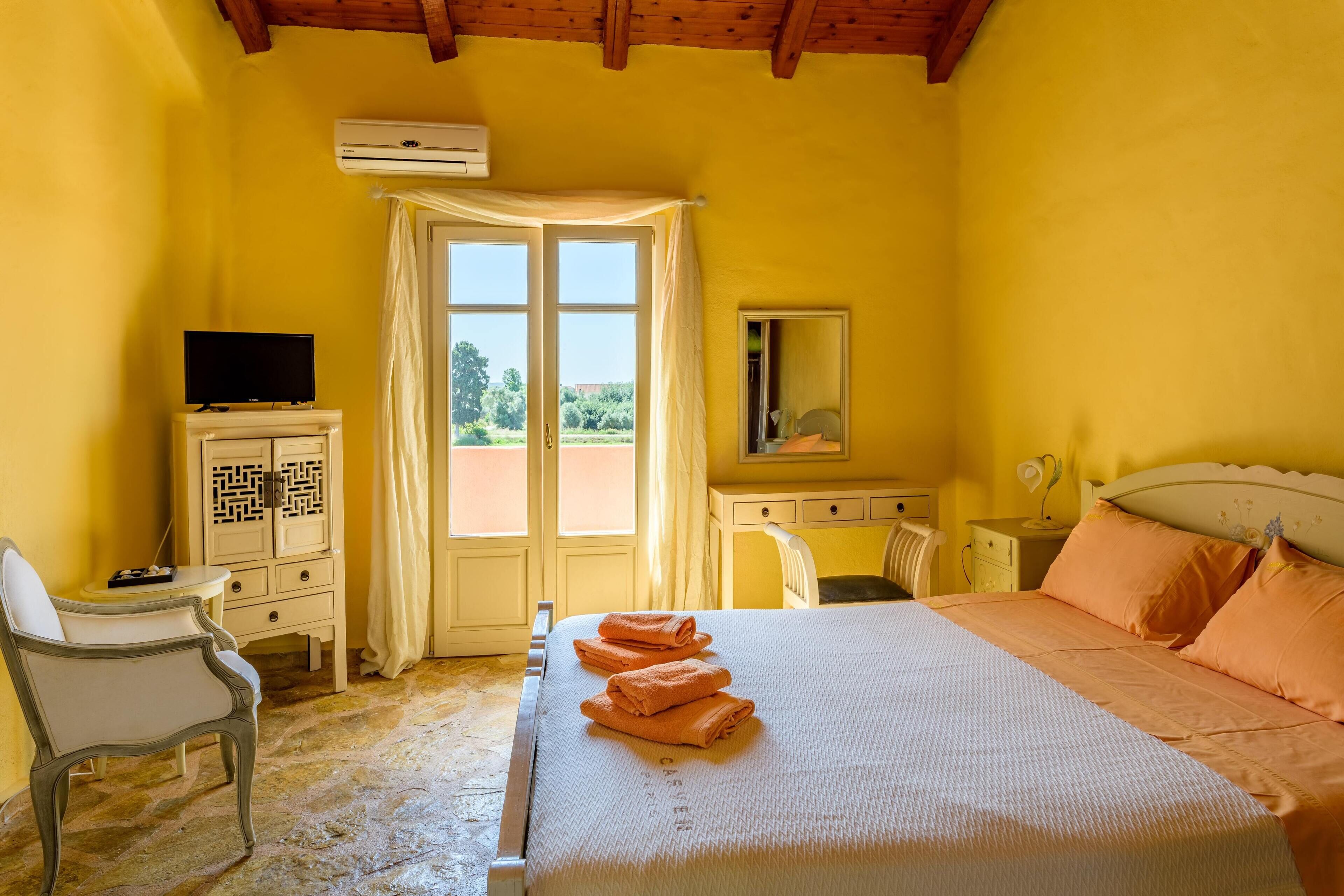 Quarto com cama, escrivaninha, cadeira e televisão.