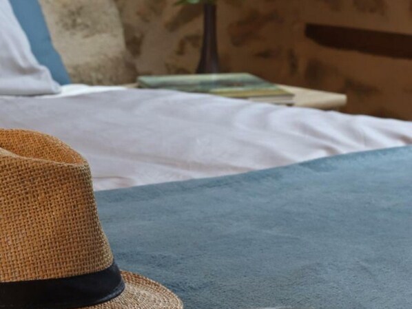 A straw hat on a bed with a blue blanket.